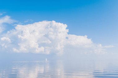 Güneşli bir günde denizdeki yelkenli muhteşem bir peri masalı üzerinde suya yansıyan bulutlarla birlikte. Lüks yat yaz macerası. Akdeniz 'de aktif tatil. Turizm ve seyahat
