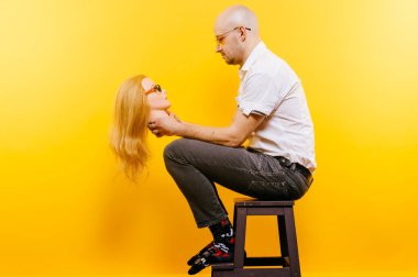 Alışılmadık kel iş adamı aşkını kaybetmeyi düşünüyor. Geçmiş mutlu ilişkilerin üzücü anıları. Gözlüklü şık bir adam sevgilisine aşık. Sarı üzerine izole edilmiş komik çift portresi. Erkek yüz ifadesi