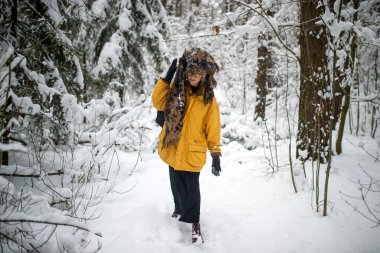 Gözlüklü, eşarplı, kar ormanında yürüyen tuhaf genç hippi kız.