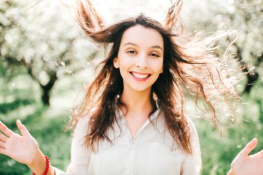 Havada bahar kokusu var. Uzun bir uykudan sonra doğanın dirilişi. Japon çiçek açan zümrüt bahçesinde narin kadın portresi. Gülümseyen mutlu kızın kadınlığı sıra dışı bir yaşam tarzı olan açık havada..