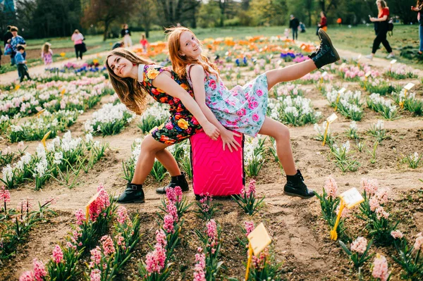 魅力的な子供とともに長い赤髪喜びとともに彼女のかなり背の高い妹リラックスと喜びで大花の庭で週末 — ストック写真