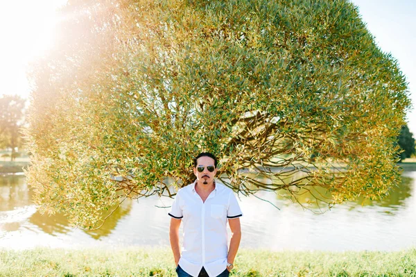 Handsome italian man portrait at nature with tree on background.