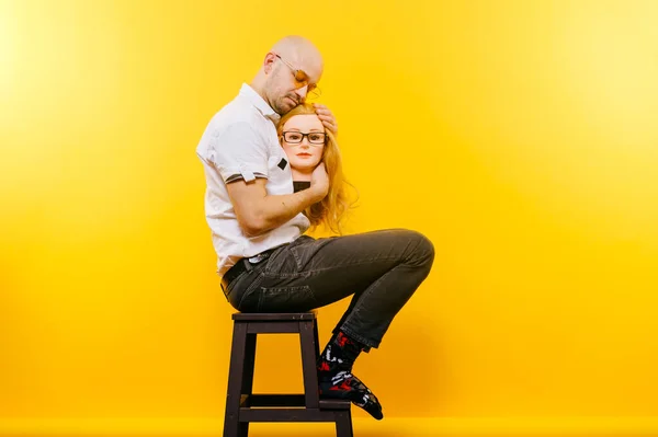 Unusual bald businessman thinking of lost love. Sad memories of happy past relationship. Stylish man in glasses in love with his girl. Funny couple portrait isolated on yellow. Male face expression