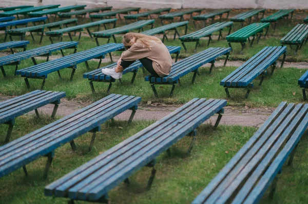 孤独凄凉的少年孤零零地坐在公园的长椅上 长满了几排荒凉的长椅 — 图库照片