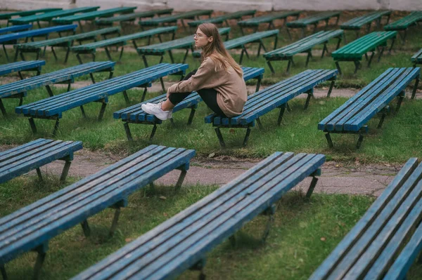 孤独凄凉的少年孤零零地坐在公园的长椅上 长满了几排荒凉的长椅 — 图库照片