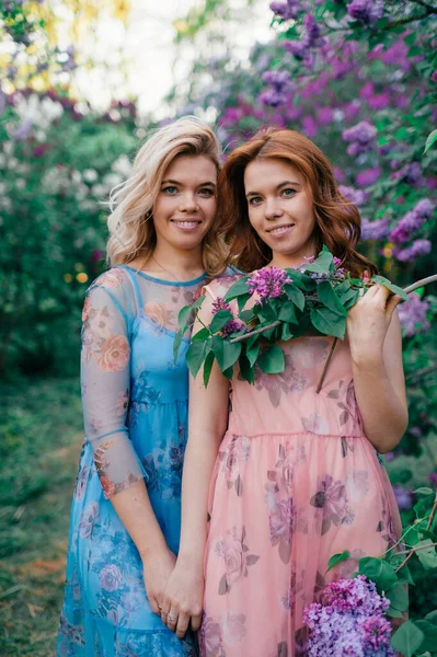 Beautiful Sisters Blonde Brown Hair Lilac Garden Hold Hands Smile — Stock Photo, Image