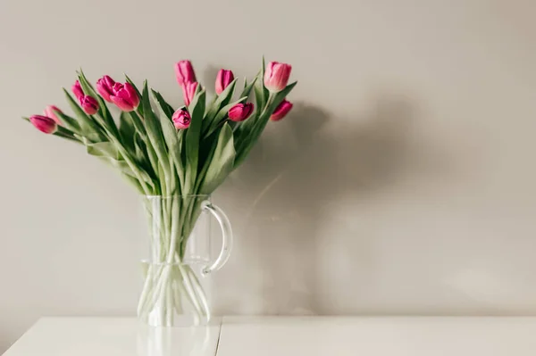 灰色の壁の背景に美しいチューリップの花束とガラス花瓶 — ストック写真