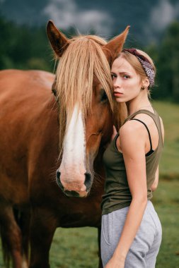 Genç güzel kız doğada ata sarılıyor..