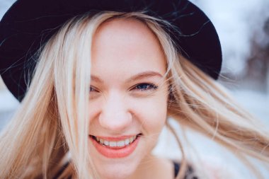 Komik gülümseyen, şık şapkalı sarışın kızın portresi. 