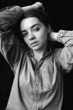 Siyah arkaplanda siyah ve beyaz bir gömlek içinde siyah ve genç bir mankenin siyah ve beyaz portresi. Farklı duygularla gülümseyen ve kameraya bakan.