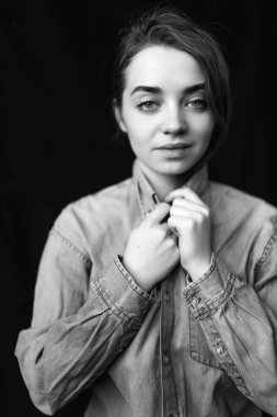 Siyah arkaplanda siyah ve beyaz bir gömlek içinde siyah ve genç bir mankenin siyah ve beyaz portresi. Farklı duygularla gülümseyen ve kameraya bakan.