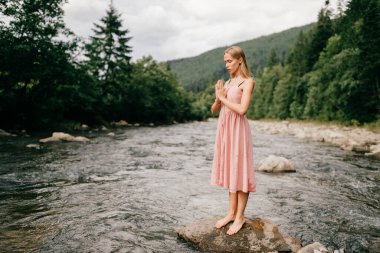 Young girl praying at nature, eyes closed clipart