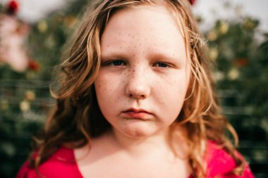 Kırmızı elbiseli, orta renk saçlı yakışıklı beyaz kız bahçede duruyor ve yazın rüyalarında bir şeyler görüyor.