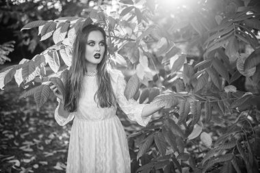 Gotik makyajlı ve komik suratlı güzel bir kız yaz parkında poz veriyor. 