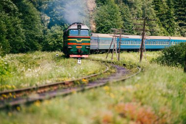 Locomotive with wagons riding railroad in carpathian mountains. People going to vacation. Train with passengers turning on railway. Travel and tourism in Ukraine. Time to rest. Reaching destination. clipart