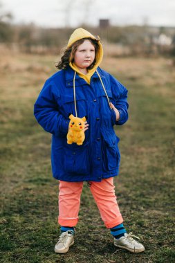 Minsk, Belarus - 8 Aralık 2019: Sıcak mavi ceketli ve küçük oyuncak pikachu 'lu sarı kapüşonlu güzel tombul köylü beyaz kız
