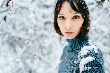 Genç bir kızın şehvetli, odak noktası portresi. Karlı bir ormanda, açık havada kameraya bakan esmer bir kadının duygusal, harika, büyük, siyah gözleri. Şefkatli, masum çocuk yüzü
