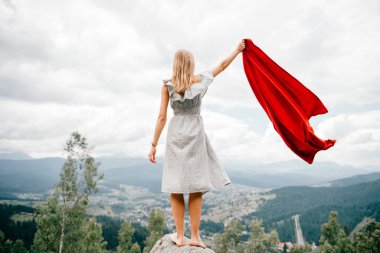 Vahşi dağlarda yaşayan bir kadın kırmızı kapaklı imdat çağrısı yapıyor. Dağlarda yürüyüş yaparken acil durum kavramı. Çıplak ayaklı kadın elinde kırmızı battaniyeyle taş üstünde duruyor ve yardım bekliyor..