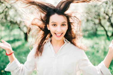 Havada bahar kokusu var. Uzun bir uykudan sonra doğanın dirilişi. Japon çiçek açan zümrüt bahçesinde narin kadın portresi. Gülümseyen mutlu kızın kadınlığı sıra dışı bir yaşam tarzı olan açık havada..