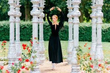 Eski moda siyah elbiseli genç balerin kemerde poz veriyor.