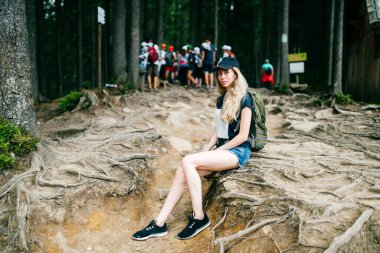 Genç, güzel sarışın bebek portresi. Sırt çantasıyla doğa gezisinde dağlarda yürüyüş yapan sevimli bir bayan gezgin. Kamp gezisindeki turist kadın. Tırabzanlara tırmanıyorum. Sıska stil kızı..