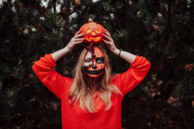 Cadılar Bayramı yüzlü genç sarışın kız dışarıda poz veriyor. Helloween kutlama konsepti.