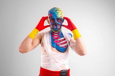 Kafasında ve omzunda beyaz tişörtle, kırmızı ve sarı eldivenli, kırmızı pantolonlu garip bir adam bir şey düşünür ve seni hipnotize eder.