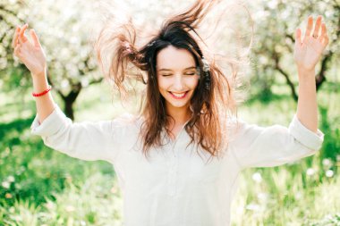 Saç atan neşeli, duygusal model kızın etkileyici portresi. Bahar geliyor. Hoş, tuhaf, tuhaf bir kadın. Bahçede çiçek açan çiçeklerle hayatın masumiyetinden zevk alıyor.