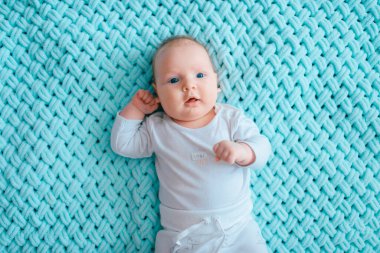 Mavi gözlü, sevimli, yeni doğmuş erkek bebek. İçeriden çekilmiş bir portresi var. Beyaz pijamayla turkuaz yün ekose üzerinde tombul yanaklı şirin bir çocuk. Komik hemşire çocuk duyguları..