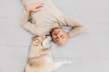 İri köpekli yetişkin kel bir adam yerde uyuyor. Evde evcil hayvanla birlikte. Nazik ve duygusal duygular. Güzel köpek, genç bir erkekle dinleniyor. Evcil hayvanlı bir adam birbirine sarılıyor..