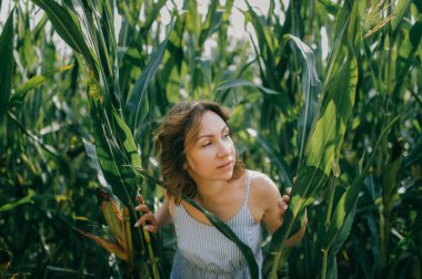 Kısa siyah dalgalı saçlı, açık mavi yazlık elbiseli çekici beyaz kadın portresi hafta sonları mısır tarlasında sükunetini koruyor..