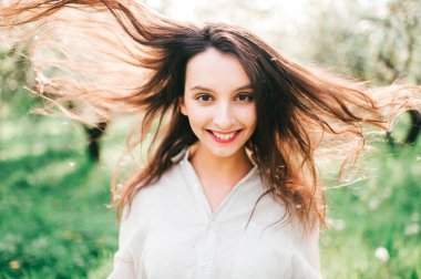 Havada bahar kokusu var. Uzun bir uykudan sonra doğanın dirilişi. Japon çiçek açan zümrüt bahçesinde narin kadın portresi. Gülümseyen mutlu kızın kadınlığı sıra dışı bir yaşam tarzı olan açık havada..