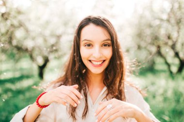 Havada bahar kokusu var. Uzun bir uykudan sonra doğanın dirilişi. Japon çiçek açan zümrüt bahçesinde narin kadın portresi. Gülümseyen mutlu kızın kadınlığı sıra dışı bir yaşam tarzı olan açık havada..