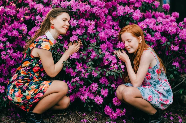 夏のドレスのかわいい女の子の写真は彼女の姉と植物園で植物を楽しんでいます — ストック写真