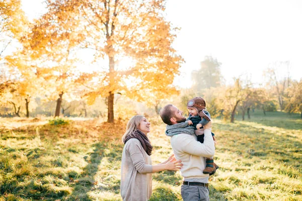 Mutlu aile çifti güneşli sonbahar parkında güzel bebeklerine sarılır..