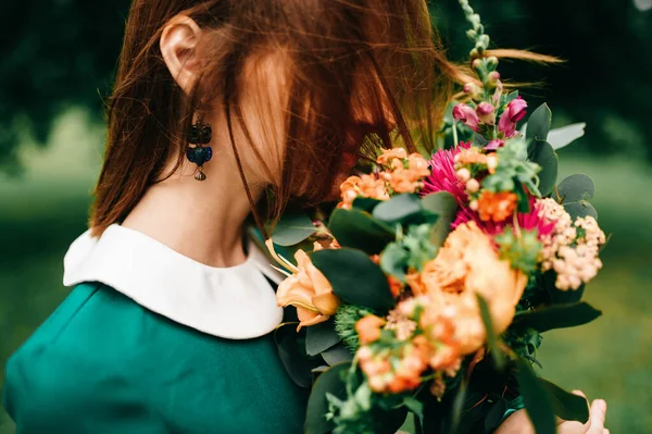 夏の花の花束と若い幸せな赤い髪の女の子は 自然の緑のドレスで内側の平和を楽しんでいます 不思議の国の公園で遊んでいる小さな子供 美しい女性の肖像画屋外 素敵な笑顔 — ストック写真