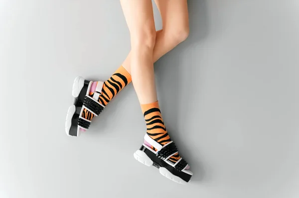 漂亮的女性腿 穿着条纹橙色时髦袜子 穿着时髦的黑色白色高楔形皮鞋 时尚女人的鞋子 穿着灰色背景的奇形怪状高跟鞋的优雅女孩的腿 — 图库照片