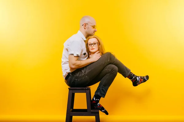 Unusual bald businessman thinking of lost love. Sad memories of happy past relationship. Stylish man in glasses in love with his girl. Funny couple portrait isolated on yellow. Male face expression