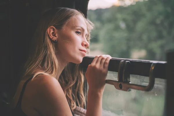 年轻美丽的金发姑娘从火车上向窗外看去 心情很好 在夏天驾驶火车的时候 漂亮的少年正享受着大自然的美丽 旅行概念 — 图库照片