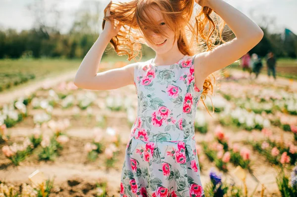 魅力的な若いですCaucasian女の子とともに長い赤髪と薄い肌で花のドレス多くの彼女の自由な時間を費やしています大花の庭 — ストック写真