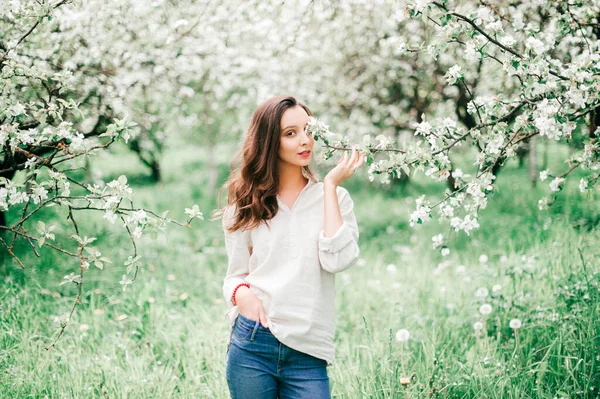 春のリンゴの木が咲きます 優しさ 容易さと女性らしさ 美しい自然の中で花を楽しむ若い素敵なブルネットの女の子 可愛いです幸せなティーン女性リラックス屋外で開花庭 — ストック写真