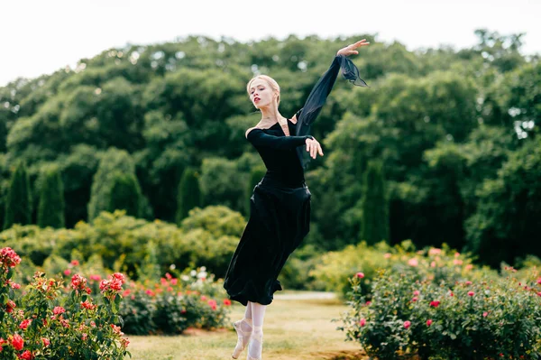 Jovem Bailarina Vestido Preto Saltando Entre Arbustos Rosa Parque — Fotografia de Stock