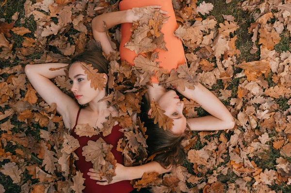 Twee Jonge Meisjes Bedekt Met Herfstbladeren Liggen Grond Kijken Naar — Stockfoto