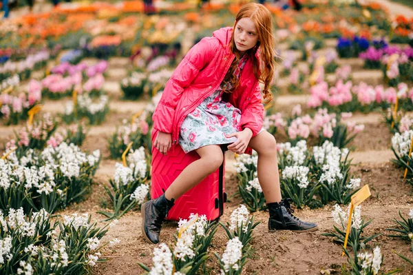 ファッション若いですモデルでピンクコートポーズのためにカメラ上の花の背景 — ストック写真