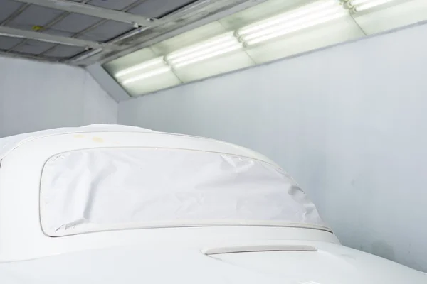Ремонт кузова: белый автомобиль в маске в лакокрасочной будке — стоковое фото