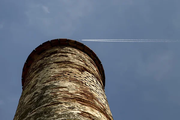 航空機の痕跡を持つ青空に対する古いタワー — ストック写真