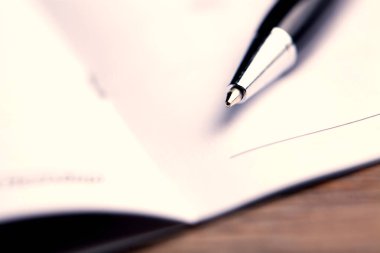 Masanın üzerinde defter olan kalem.