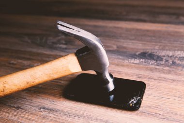 Çekiç ve ezilmiş telefon masada.