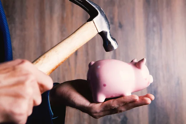 A sad pink piggy bank is about to be hit by a hammer in old vintage tone  Financial problem