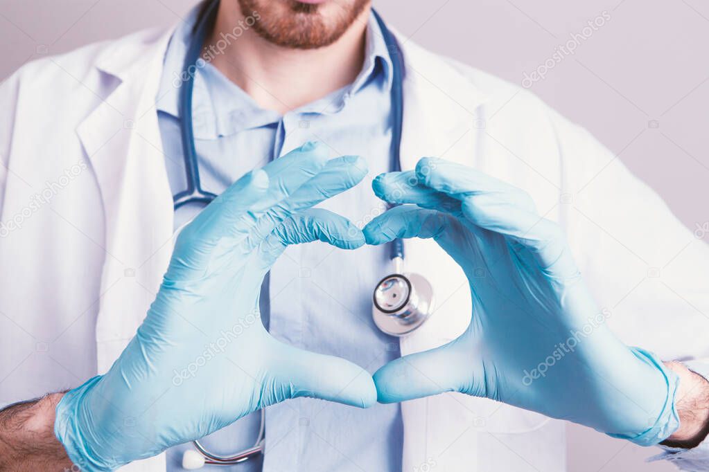 Heart shaped hand in medical gloves